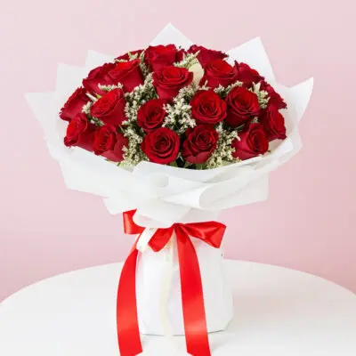 A bouquet of vibrant red roses tied with a matching red ribbon, elegantly arranged for a special occasion.