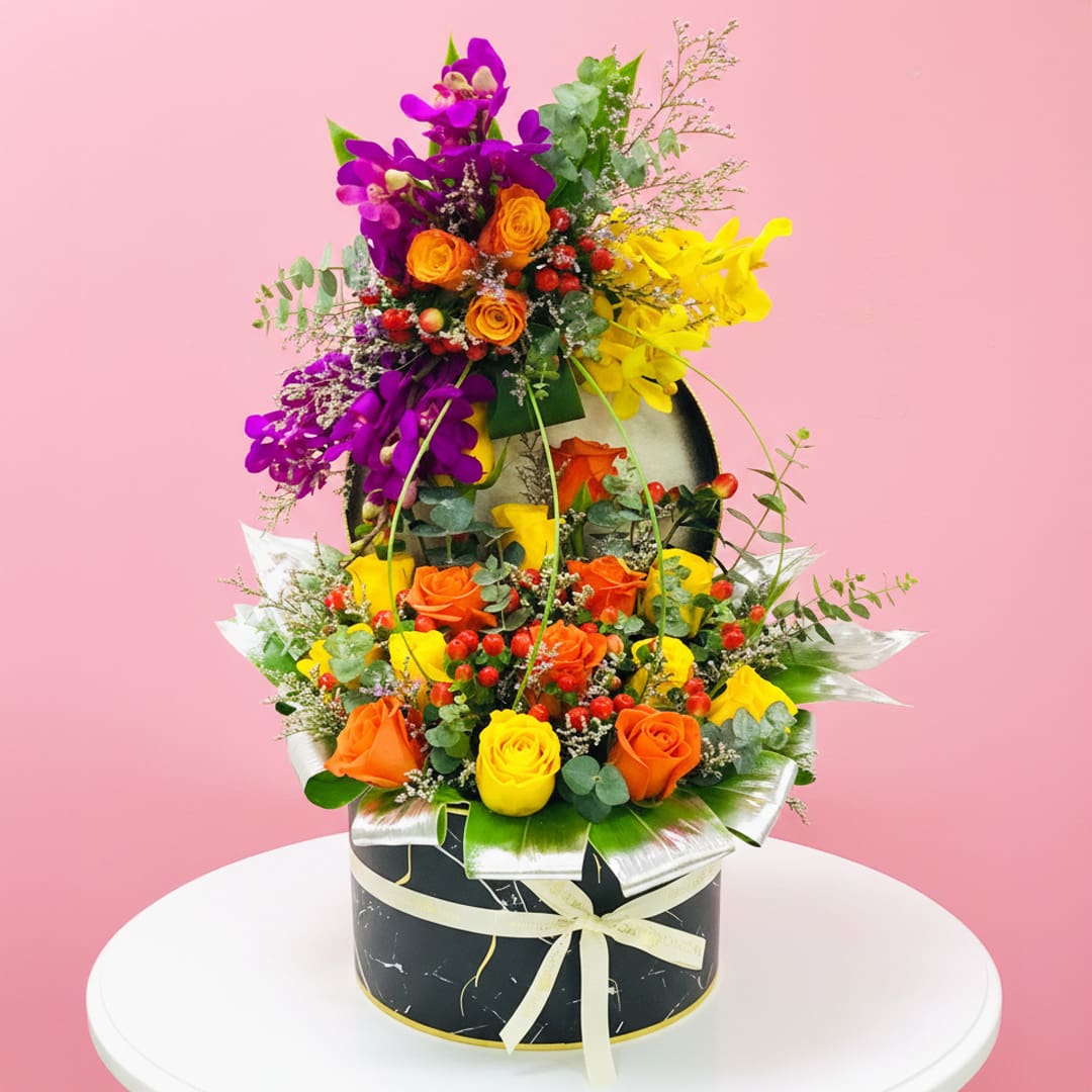 Regal Floral Basket-16-10 A vibrant assortment of flowers arranged in a sleek black box, showcasing a variety of colors and textures.