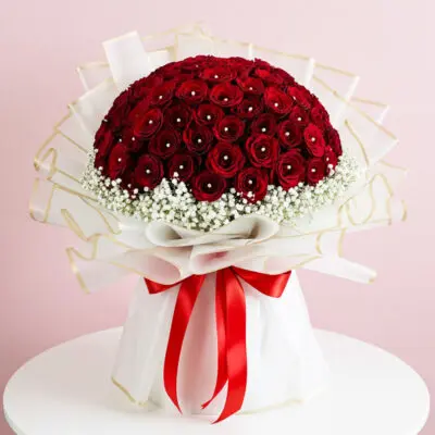 A vibrant bouquet of red roses surrounded by delicate white baby's breath flowers.