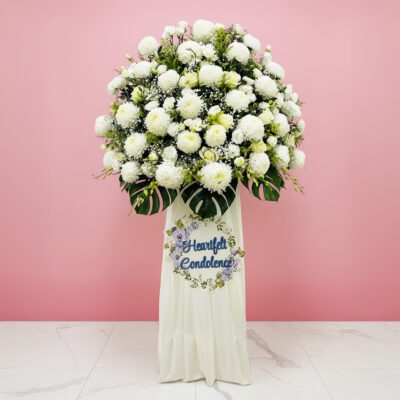 A white funeral flower arrangement beside a sign that reads "Heartfelt Condolence," conveying a heartfelt message.
