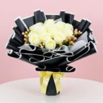 A bouquet of white roses tied with a yellow ribbon, elegantly arranged for a special occasion.