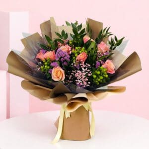 A bouquet of pink and purple roses wrapped in a brown paper bag, symbolizing love and happiness for special occasions.