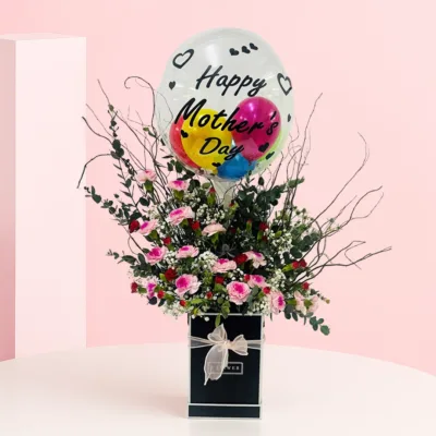 A vibrant flower arrangement with a colorful balloon, perfect for sending love to Mom this Mother’s Day.