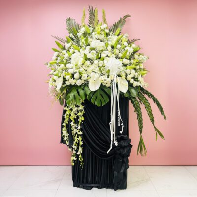 A large black and white sympathy arrangement featuring various flowers in an elegant display.