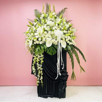 A large black and white sympathy arrangement featuring various flowers in an elegant display.