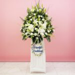A white stand filled with white flowers beside a sign that reads "Heartfelt Condolence"