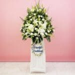 A white stand filled with white flowers beside a sign that reads "Heartfelt Condolence"