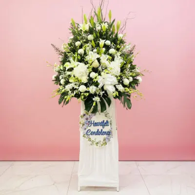 A white stand filled with white flowers beside a sign that reads "Heartfelt Condolence"