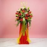 A vibrant red and yellow flower arrangement atop a stand, celebrating a grand opening event.