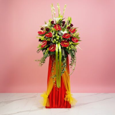 A vibrant red and yellow flower arrangement atop a stand, celebrating a grand opening event.