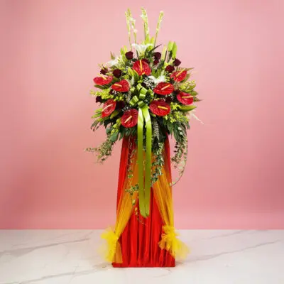 A vibrant red and yellow flower arrangement atop a stand, celebrating a grand opening event.