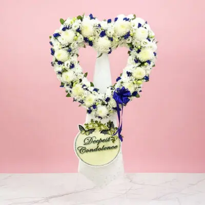 Heart-shaped wreath adorned with blue and white flowers, symbolizing love and tranquility.