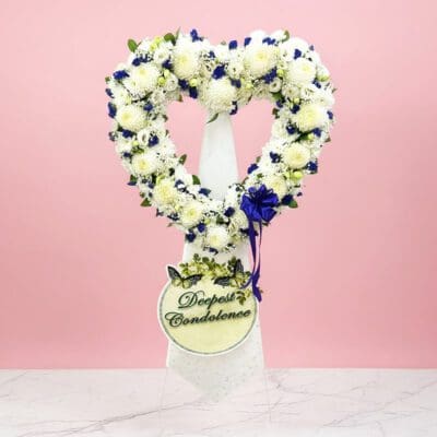Heart-shaped wreath adorned with blue and white flowers, symbolizing love and tranquility.