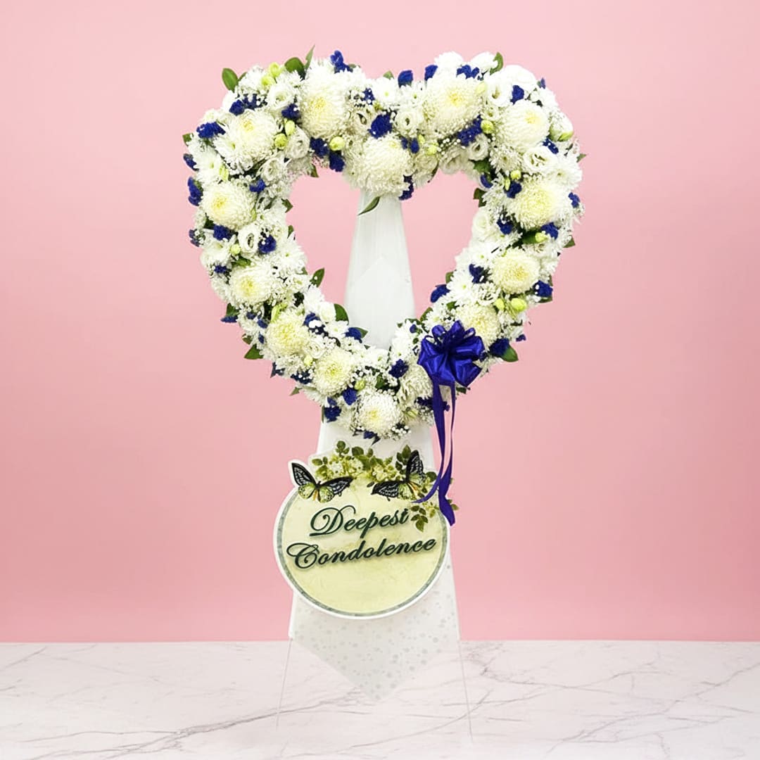 Gentle Remembrance Floral Stand-0000178 Heart-shaped wreath adorned with blue and white flowers, symbolizing love and tranquility.