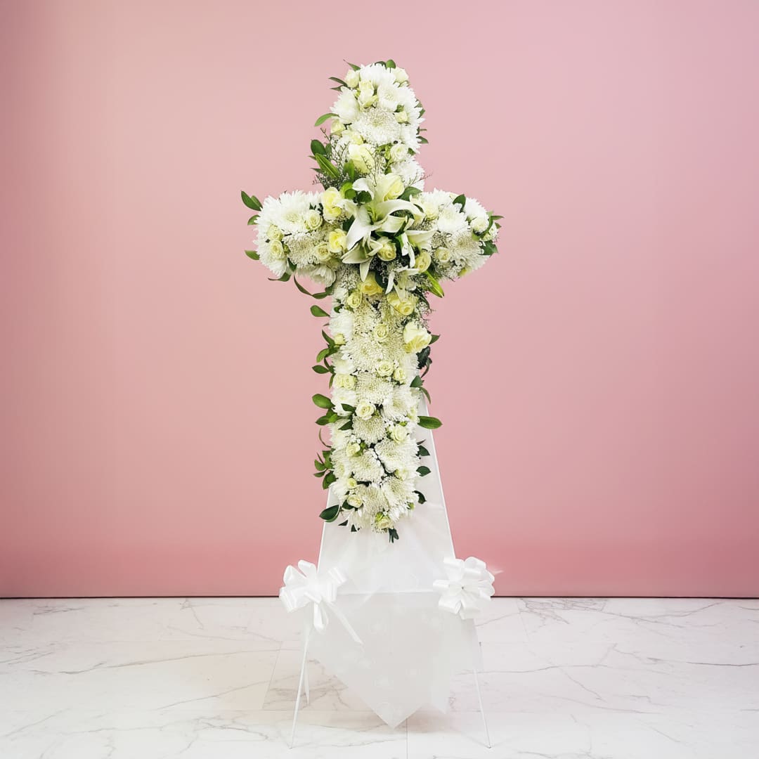 Graceful White Cross Tribute A white cross with colorful flowers displayed on a light pink background.