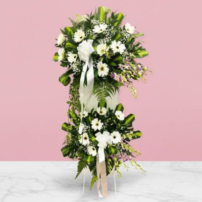 Elegant white floral arrangement of daisies surrounded by lush greenery, symbolizing sympathy and cherished memories.
