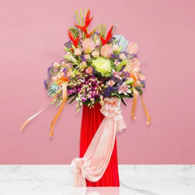 A lively floral arrangement in a vase on a pink wall, bursting with colors that convey hope and the spirit of fresh starts.