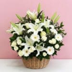 A basket filled with white flowers condolence set against a soft pink background.