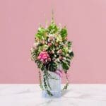 A decorative arrangement of pink flowers and lush green leaves, featured at the vibrant beginnings opening stand.