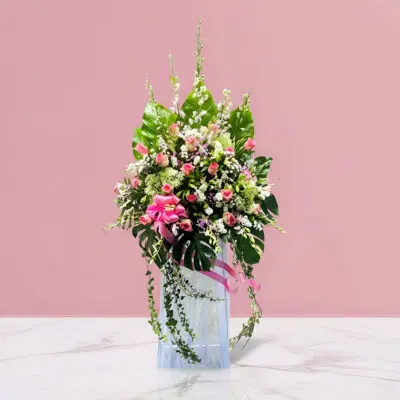 A decorative arrangement of pink flowers and lush green leaves, featured at the vibrant beginnings opening stand.