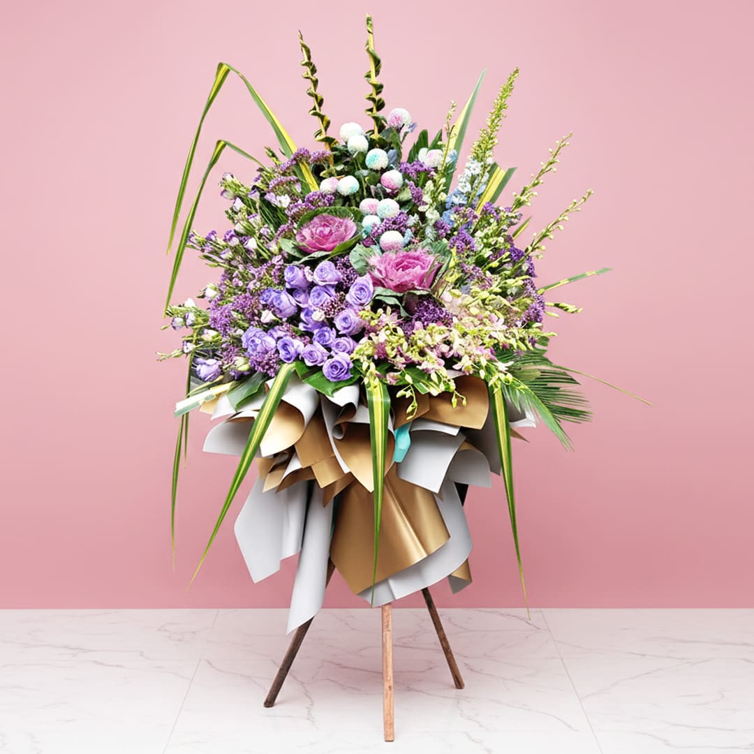 Enchanting Blossoms Opening Stand Elegant floral arrangement in purple and pink on a stand, set before a pink wall, ideal for weddings and corporate events.