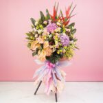 A vibrant bouquet of flowers on a stand against a pink wall, symbolizing success and elegance in any space.
