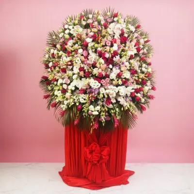A large, vibrant floral arrangement in a red vase, showcasing delicate blooms designed to enhance any décor.