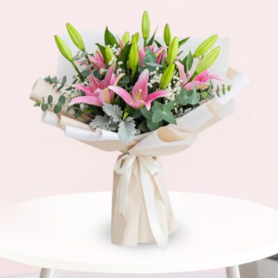 A vibrant bouquet featuring pink lilies surrounded by fresh eucalyptus leaves.