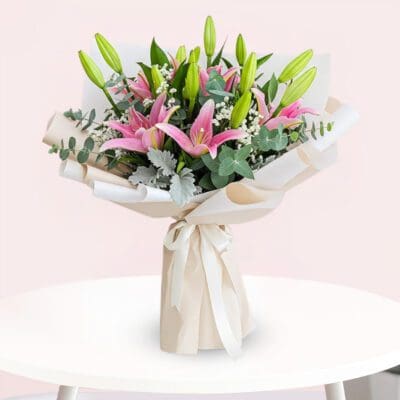 A vibrant bouquet featuring pink lilies surrounded by fresh eucalyptus leaves.