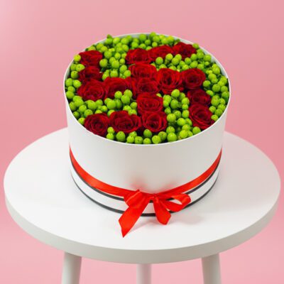 A white box filled with vibrant red roses and lush green leaves, creating a striking floral arrangement.