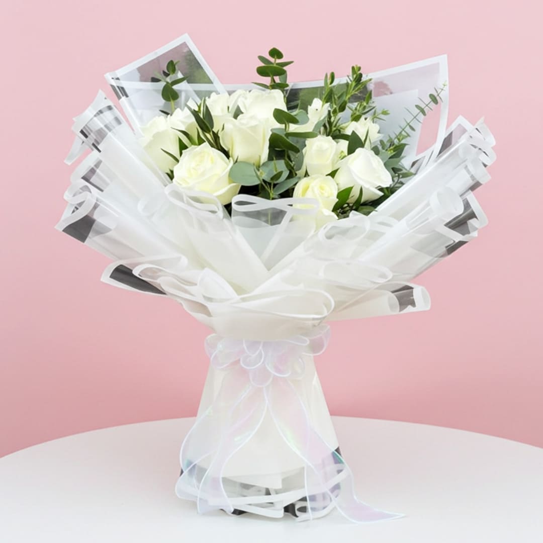 Heavenly White Whispers-03-12-01 A hand bouquet of ten white roses and eucalyptus in a clear vase, elegantly arranged for a fresh and classic look.