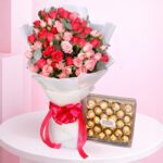 A romantic arrangement of roses and Ferrero chocolates on a table, named Sweetheart’s Ferrero Rose Surprise.