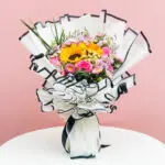A colorful bouquet of flowers accompanied by a greeting card, placed elegantly on a wooden table.