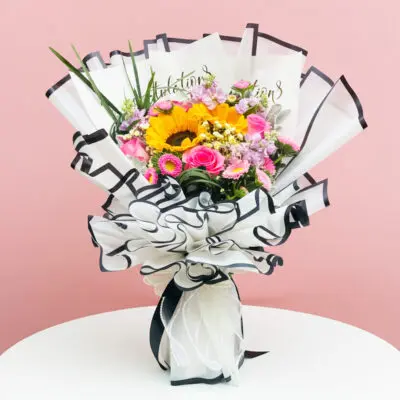A colorful bouquet of flowers accompanied by a greeting card, placed elegantly on a wooden table.