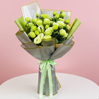 A bouquet of green roses tied with a ribbon, elegantly arranged on a table.