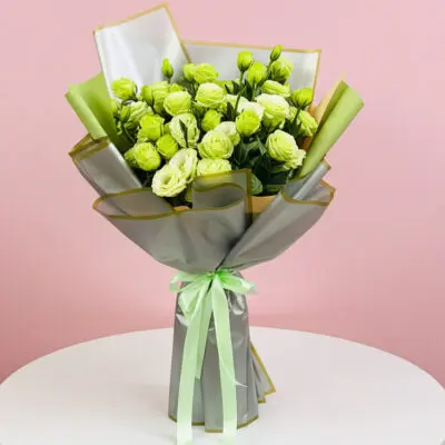 A bouquet of green roses tied with a ribbon, elegantly arranged on a table.