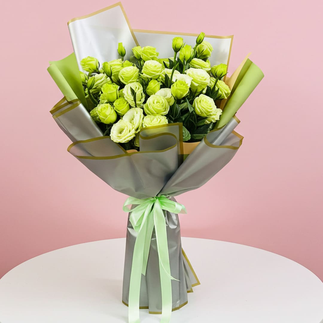 Radiant Meadow Greens Bouquet-01 A bouquet of green roses tied with a ribbon, elegantly arranged on a table.