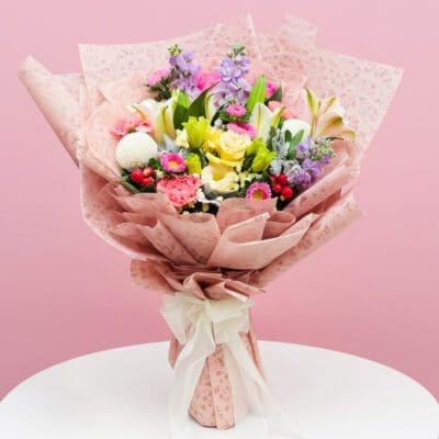 A vibrant bouquet of flowers displayed against a soft pink background.