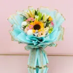 A vibrant bouquet of flowers wrapped in blue paper, showcasing a variety of colorful blooms.