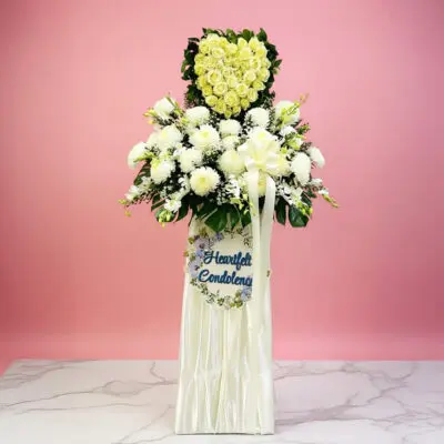 A white stand filled with white flowers beside a sign that reads "Heartfelt condolences."