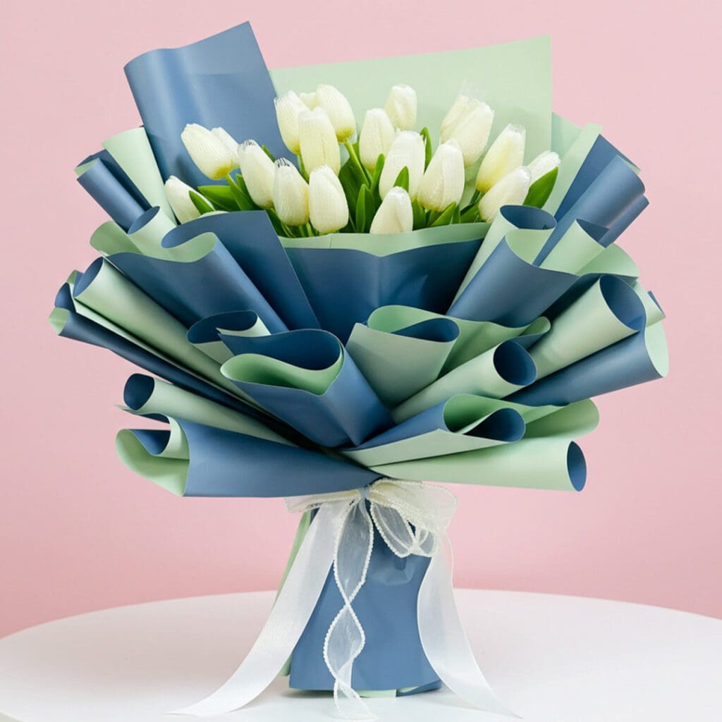 A bouquet of white tulips elegantly wrapped in blue and green ribbons, showcasing a fresh and vibrant floral arrangement.
