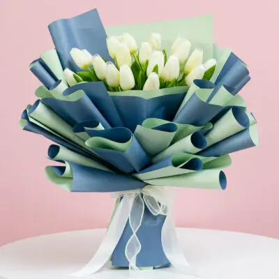 A bouquet of white tulips elegantly wrapped in blue and green ribbons, showcasing a fresh and vibrant floral arrangement.