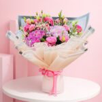 A vibrant hand bouquet with pink hydrangeas, eustoma, and baby breaths, complemented by greens, suitable for all occasions.