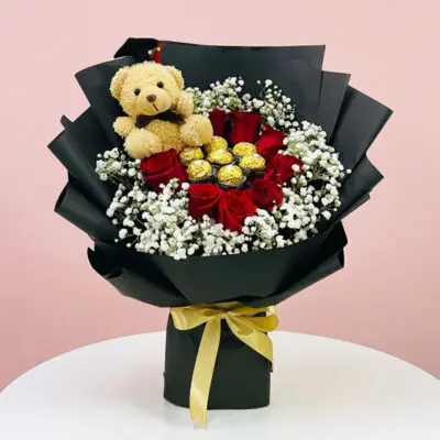 A Graduation Bouquet Featuring Roses, Chocolates, And A Teddy Bear, Symbolizing Celebration And Achievement.