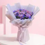 A bouquet featuring vibrant purple roses alongside delicate blue flowers, arranged elegantly.