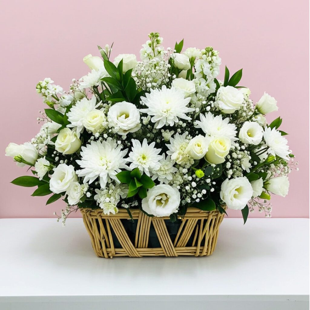 A basket filled with white flowers sits elegantly on a wooden table.