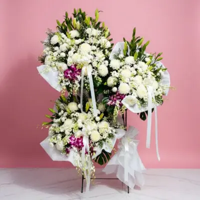 A decorative wreath with pink and white framing set on a pastel pink background, enhancing its charming appearance.