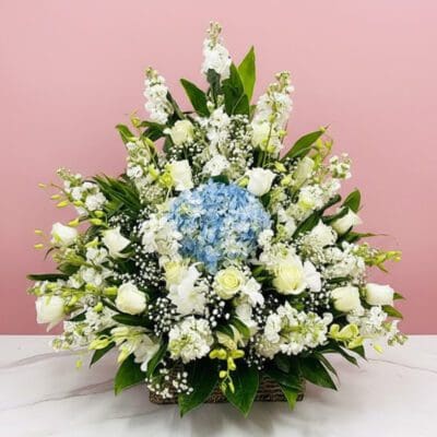 A basket arrangement of white and blue sympathy flowers, conveying a sense of peace and remembrance.