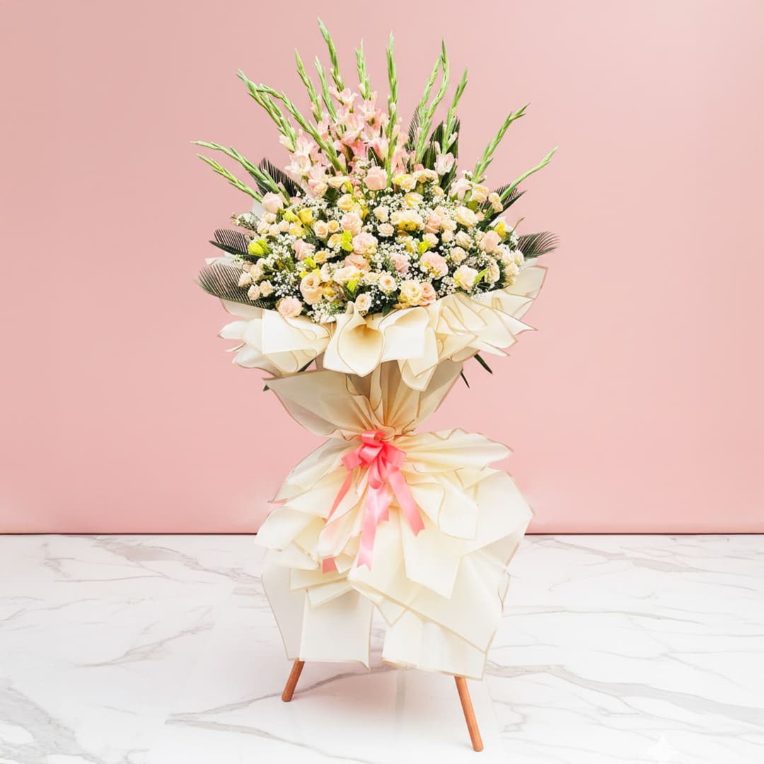 Radiant Blooms Welcome Stand-04-02-2501 A vibrant bouquet of assorted flowers, including Eustoma and roses, in a vase against a soft pink background.