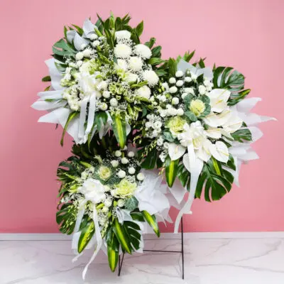 A large floral arrangement for sympathy or funeral featuring various blooms on a light pink background.